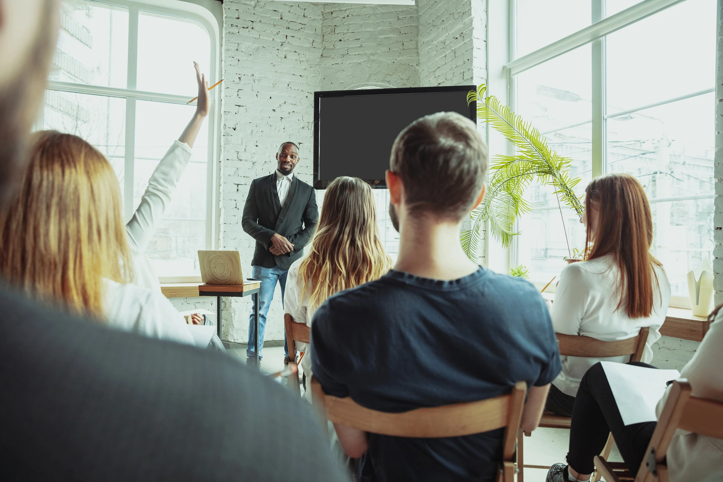 Question. Male african-american speaker giving presentation in hall at workshop. Audience or hall. Rear view of participants. Conference event, training. Education, diversity, inclusive concept.